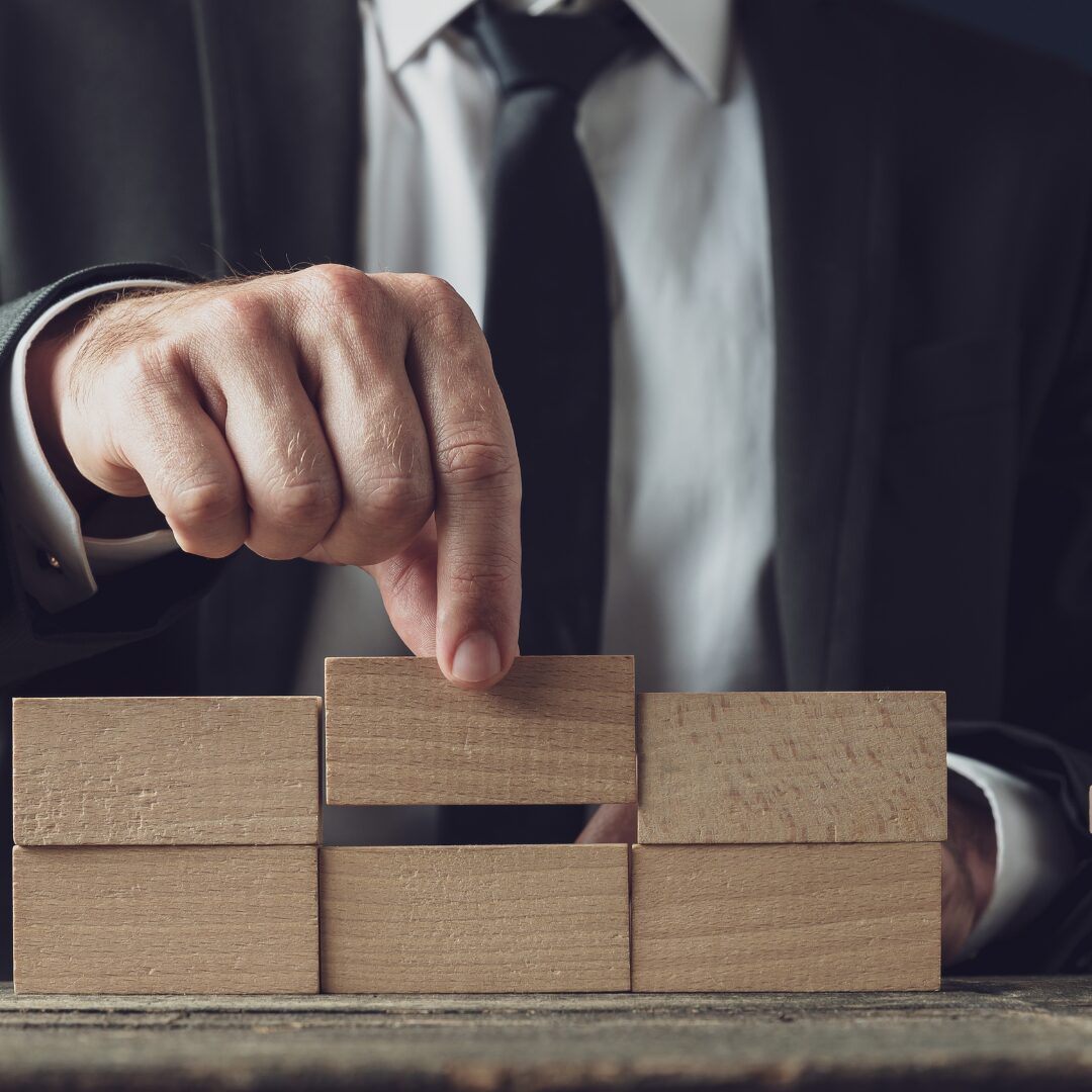 Holzklöze und 2 Finger die einen Stein entnehmen